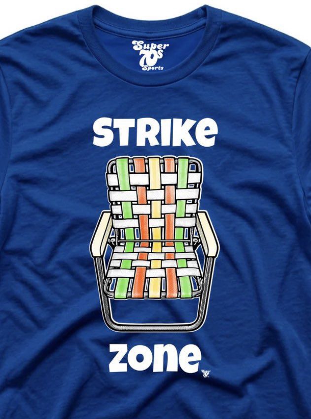 A royal-blue Super 70s Sports t-shirt reading "STRIKE zone" around a drawing of a webbed aluminum lawn chair, a nod to the backyard Wiffle-ball lawn-chair catcher.